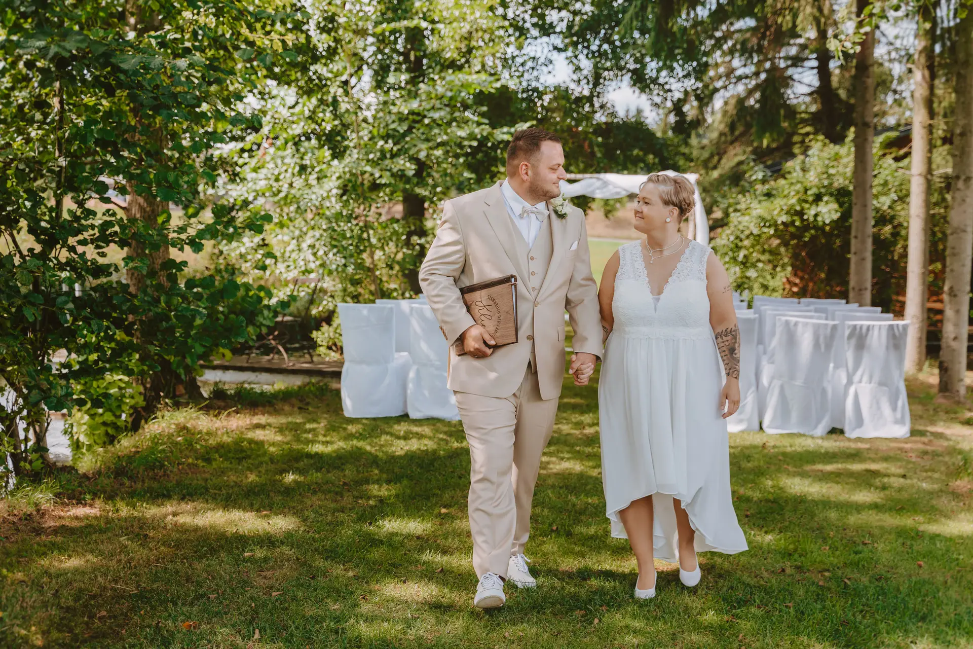 Hochzeitspaar läuft auf grüner Wiese Hand in Hand